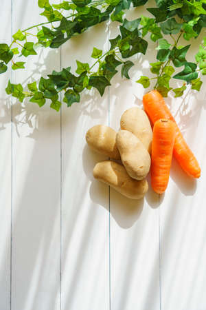 Raw unpeeled potatoes and carrots on the wooden tableの写真素材