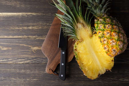 Fresh pineapple and cutting board on wooden tableの写真素材