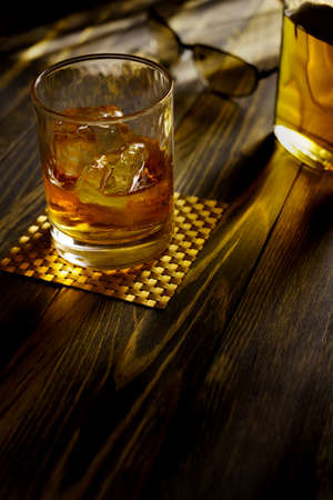 Whiskey in a glass with ice on a wooden table