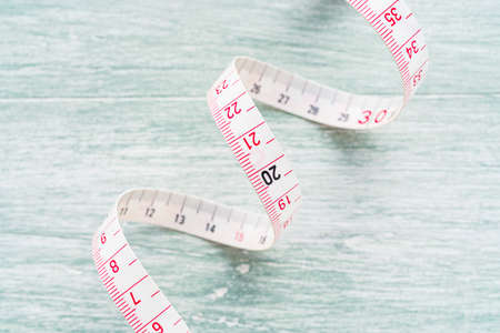 White measuring tape isolated on wooden table