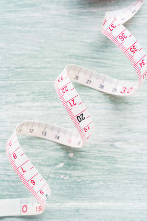 White measuring tape isolated on wooden table