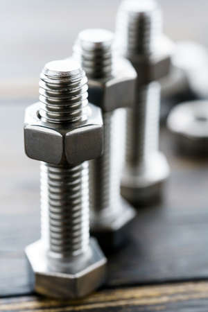 Steel nuts and bolts close-up on wooden table
