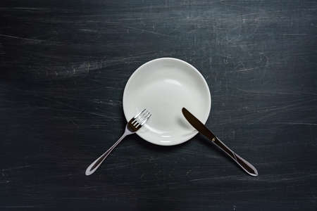 Empty plate, knife and fork on wooden table