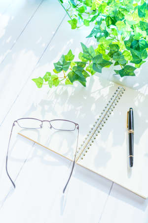 Notebook, pen and glasses on wooden tableの写真素材