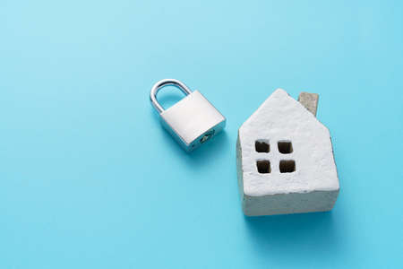 Padlock and miniature house on color backgroundの写真素材