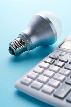 Calculator and led light bulb isolated on color backgroundの写真素材