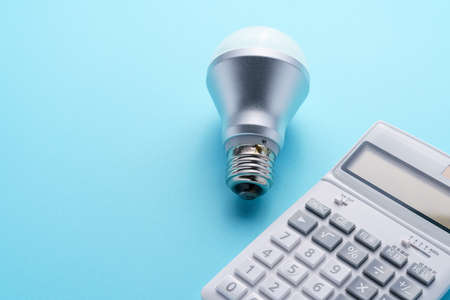 Calculator and led light bulb isolated on color backgroundの写真素材