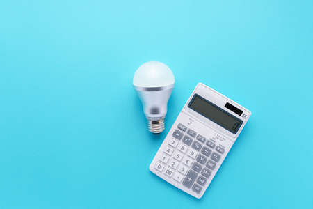 Calculator and led light bulb isolated on color backgroundの写真素材