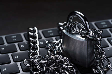 Computer keyboard and Padlock with chain on dark background