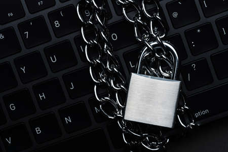 Computer keyboard and Padlock with chain on dark background