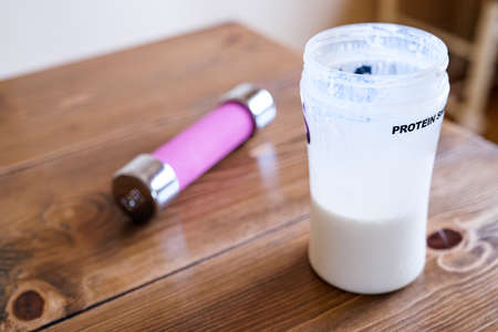 Protein drink and dumbbell on wooden tableの写真素材