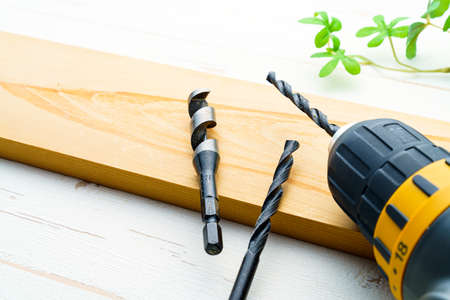 Drill bits on wooden table. (Closeup of drill and hole in the piece of wood)の写真素材