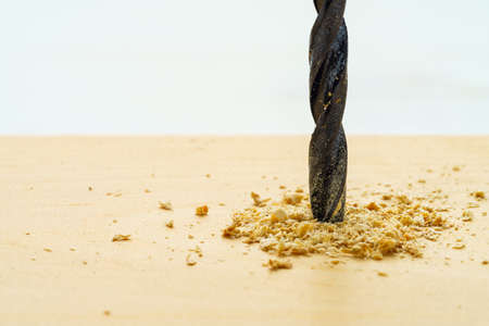 Drill bits on wooden table. (Closeup of drill and hole in the piece of wood)の写真素材