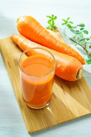 Carrot juice in glass isolated on wooden tableの写真素材