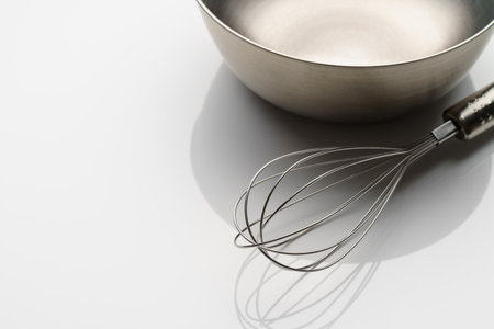stainless whisk and bowl on white backgroundの写真素材