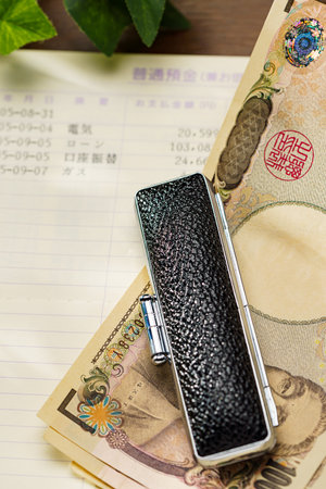 Japanese money and bankbook on wooden tableの写真素材