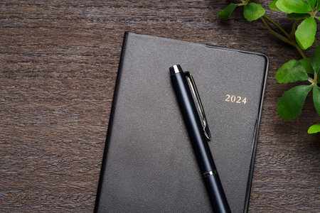 2024 Notebook and pen on wooden table (2024 schedule book)の写真素材