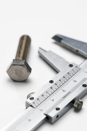 Metal vernier caliper and bolt on white background