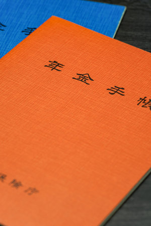 Japanese pension insurance booklet on wooden table. (Written 'pension book')の写真素材