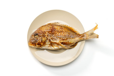 Grilled whole sea bream served on a plate on white backgroundの写真素材