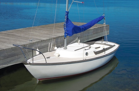 Small Sailboat :  A small white boat waits at a wooden dock.