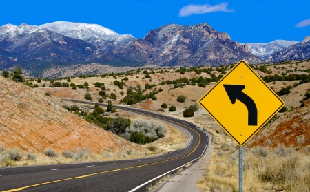 Curve Warning Sign:  A road sign alerts motorists to a curving mountain road in northern New Mexico.の写真素材