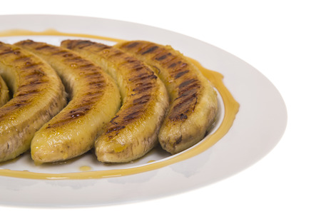 fried bananas with honey on a plate on the isolated backgroundの写真素材