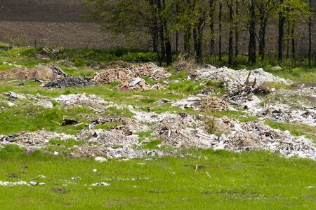 Unauthorized dump. Heaps of construction debris lie on the green grass