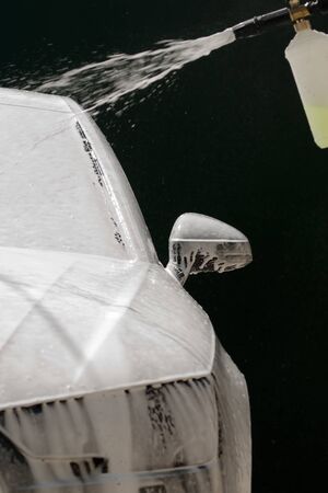 Water and foam under pressure flies toward the car body. Close-up viewの写真素材