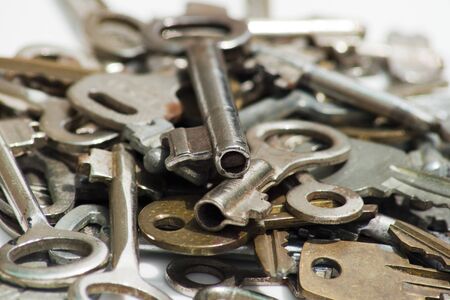 Heap of different keys to the locks lie on a white surfaceの写真素材