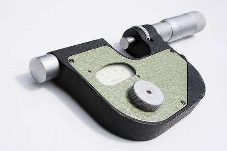 Precise measuring instrument - micrometer or indicator-type bracket lies on a white surfaceの写真素材