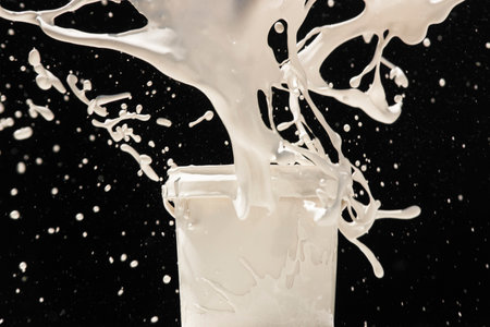 Splashing paint from a can. White paint splashing out of plastic can on black backgroundの写真素材
