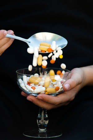 Taking medication with a tablespoon from a glassの写真素材