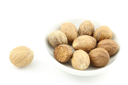 composition of nutmeg seeds in a small white bowlの写真素材