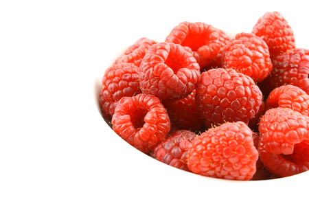 fresh red raspberry fruits in a small white bowl