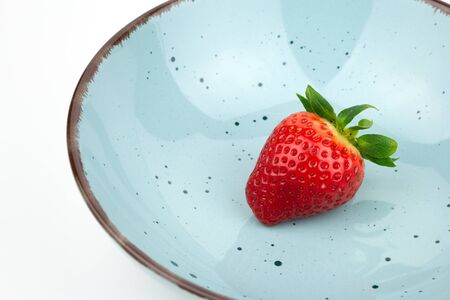 fresh garden strawberry fruit in a blue bowl closeupの写真素材