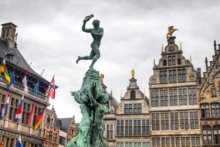 The city hall on the central market place in Antwerp in Belgium, with many flags and the statue in...