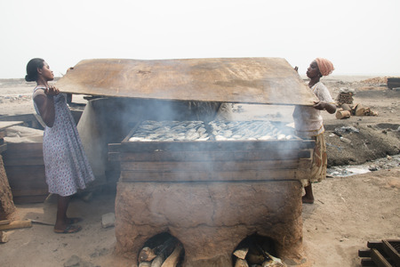 ACCRA, GHANA - JANUARY 2016: Two women smoking fish in their home in Jamestown, Accra, Ghana at the Gulf of Guineaのeditorial素材