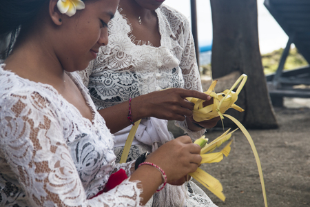 PEMUTERAN, BALI - JANUARY 2018: A group of women in Bali, Indonesia preparing the daily offerings with food and flowersのeditorial素材