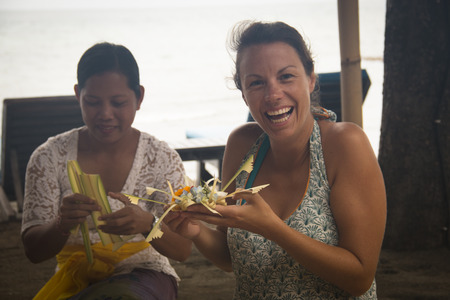 PEMUTERAN, BALI - JANUARY 2018: A group of women in Bali, Indonesia preparing the daily offerings with food and flowersのeditorial素材