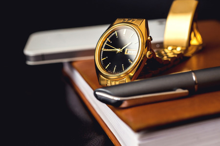 Men accessory, golden watch, pen and mobile phone on the leather diary.の写真素材