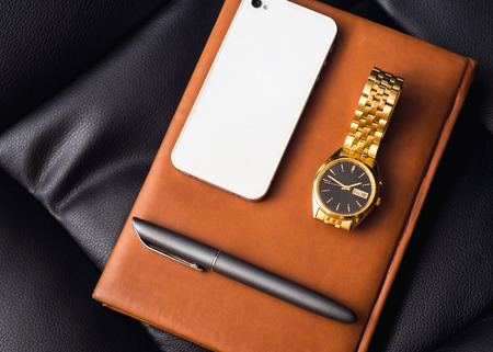Men accessory, golden watch, pen and mobile phone on the leather diary.の写真素材