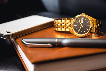 Men accessory, golden watch, pen and mobile phone on the leather diary.の写真素材