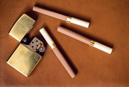 Men's accesory, golden lighter and cigarettes on a brown leather background..の写真素材
