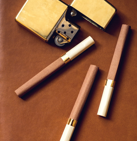 Men's accesory, golden lighter and cigarettes on a brown leather background..の写真素材