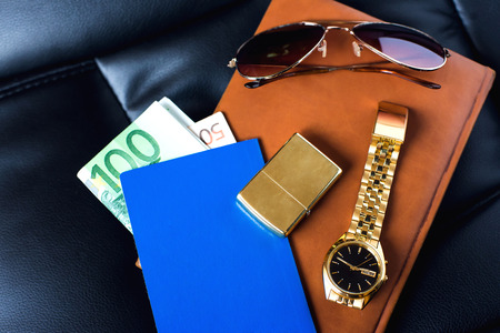 Traveller's accesory, passport, money, golden watch, sunglasses and lighter on the leather diaryの写真素材