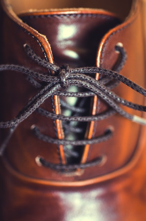 A vertical close up of laces on a brown leather business shoe.の写真素材