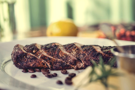 Delicious beef steak with tomato sauce, melon and rosemary, decorated with coffee beans on the plate, wooden table. autumn concept. Selective focus.の写真素材