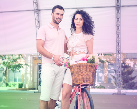 Couple with pink vintage bicycle in the summer park. Outdoor shot.の写真素材