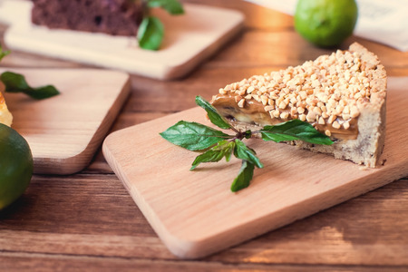 Pieces of nut cake decorated with mint and lime on wooden table.の写真素材